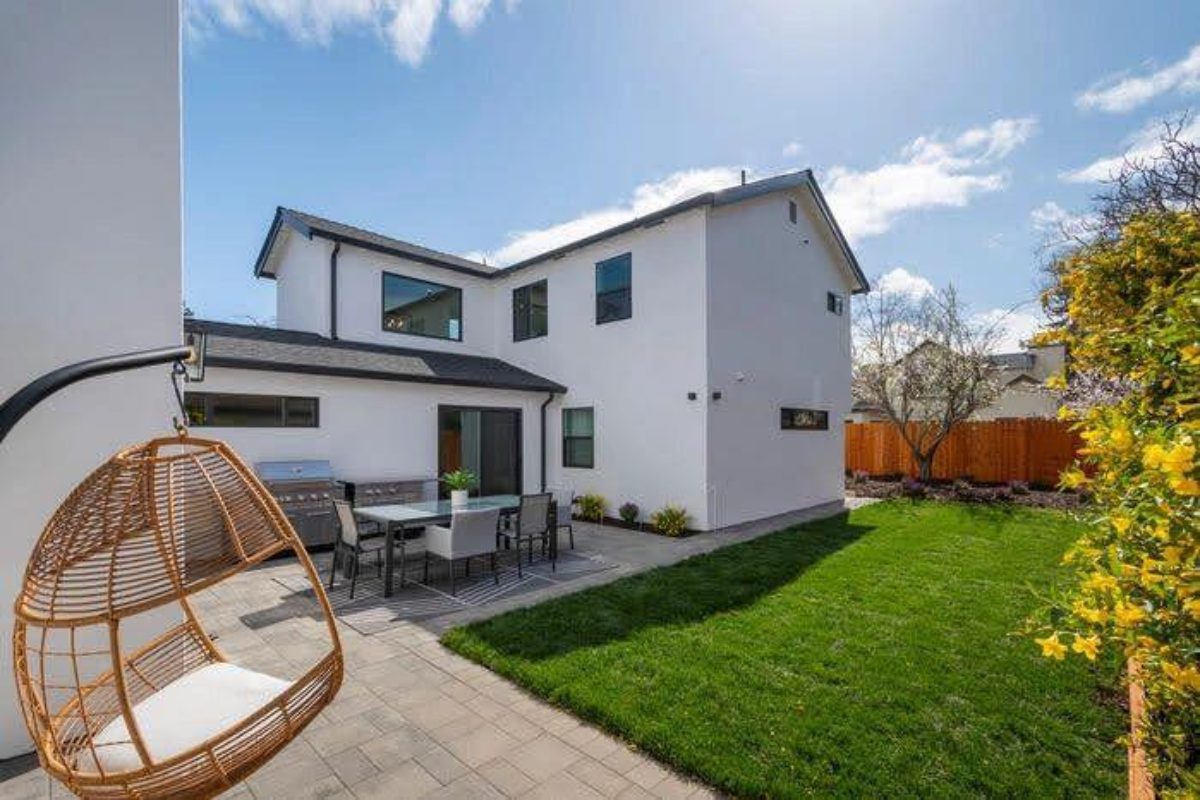 A backyard with a lawn and patio furniture.