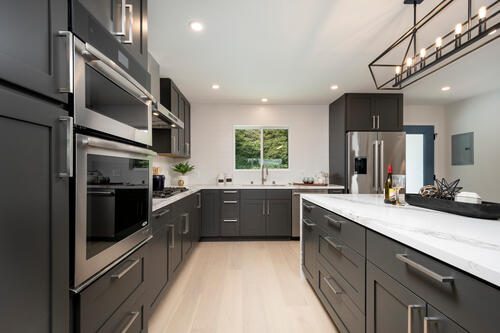 A kitchen with grey cabinets and white counters.